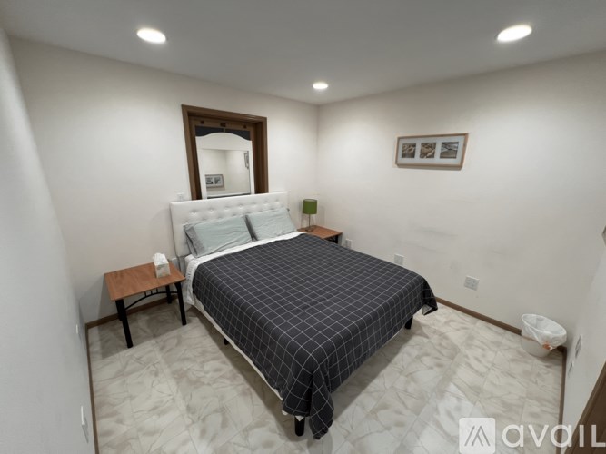 A bedroom with a bed, nightstand, and a mirror on the wall.