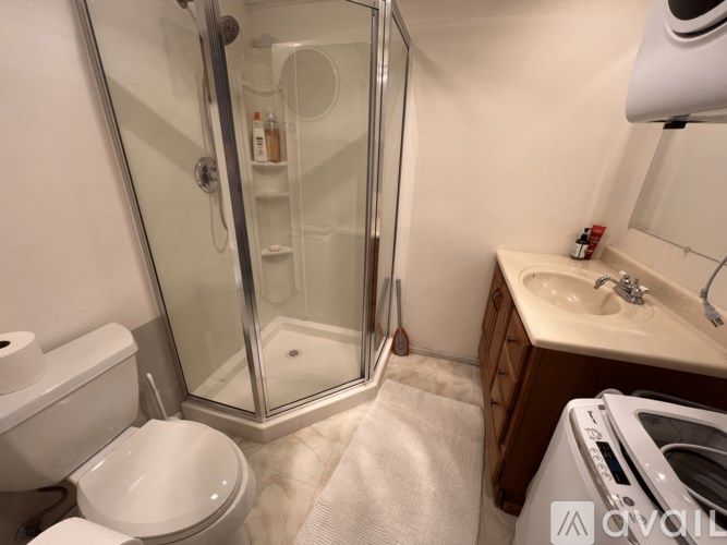 A small bathroom with a toilet, sink, and shower.