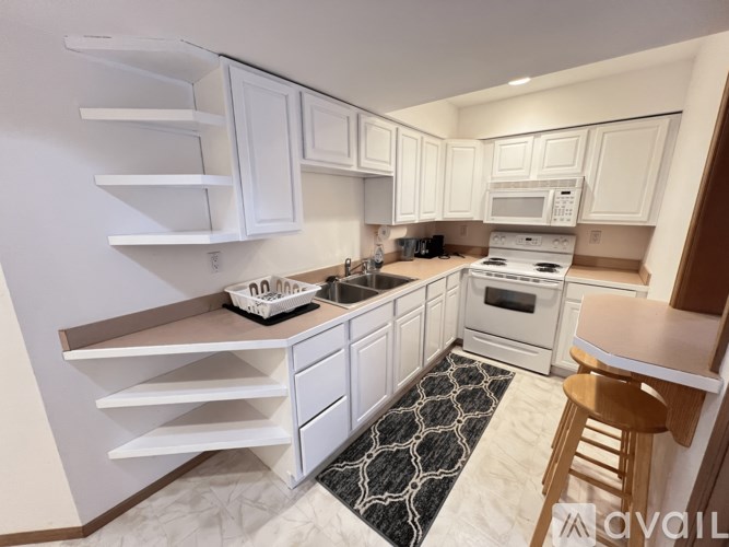 A kitchen with white cabinets and a black and white rug on the floor.