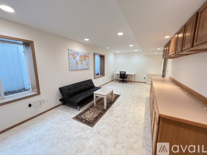 A living room with a black sofa and a world map on the wall.