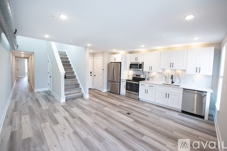 A spacious kitchen and living area with white cabinetry and a wood floor.