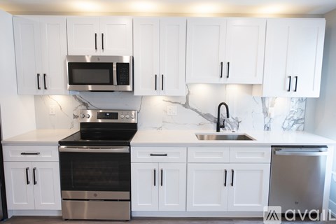 A kitchen with white cabinets and a black stove top oven.