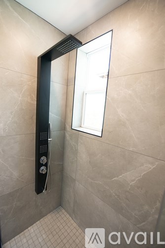 A bathroom with a tiled floor and a shower with a glass door.