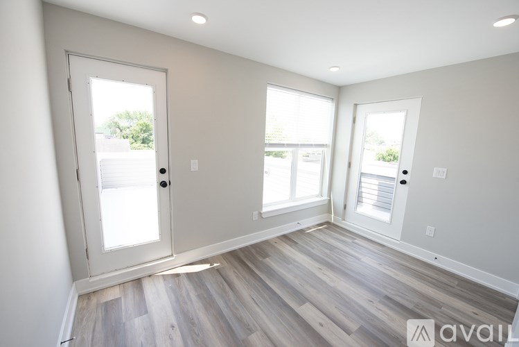 A room with a door, two windows, and a wooden floor.