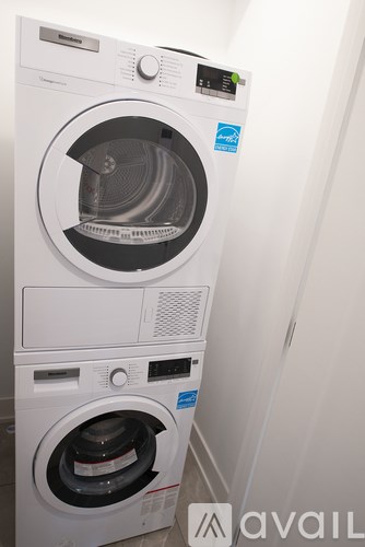 A stack of white front loading washing machines with the door of the top one open.