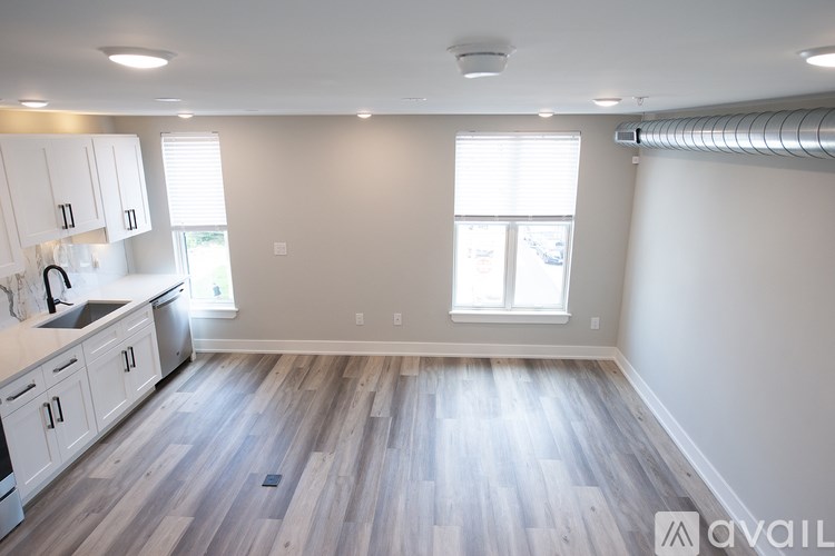 A spacious kitchen with white cabinets and a wooden floor.