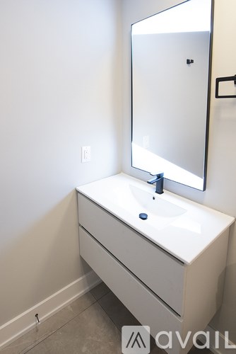 A white sink with a blue faucet and a mirror above it.