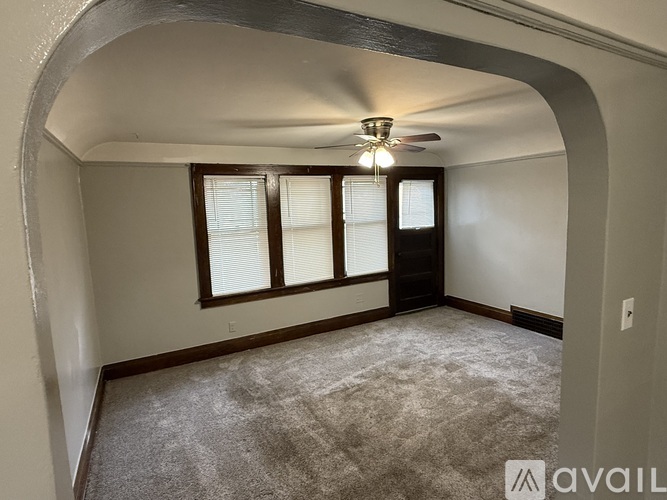 A room with a carpeted floor and a ceiling fan.