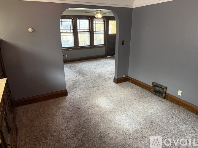 A spacious room with a carpeted floor and a window with a view of a building outside.