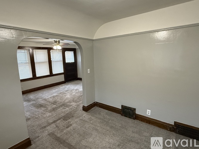 A room with a carpeted floor and a window with blinds.