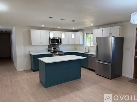 A kitchen with a large island in the middle and a refrigerator to the right.
