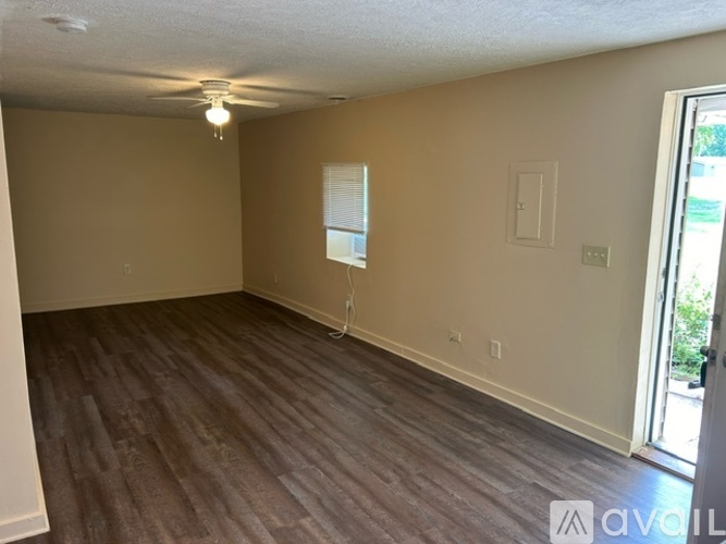 A room with wooden flooring and a window with blinds.
