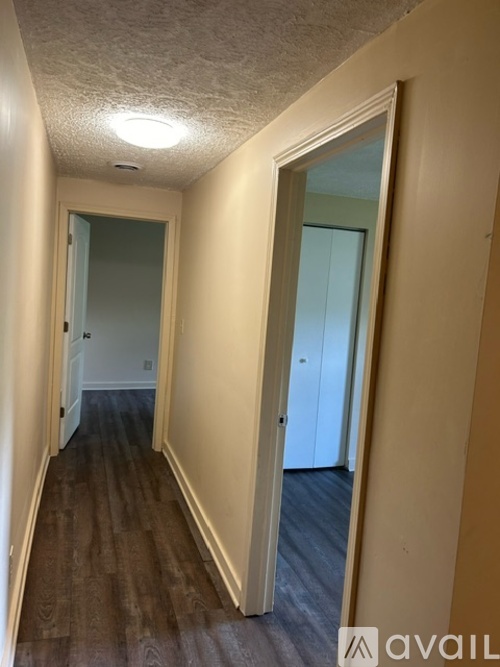 A hallway with wooden floors and white walls.