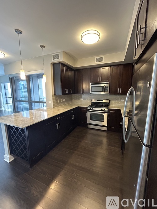 A modern kitchen with dark wood cabinets and stainless steel appliances.