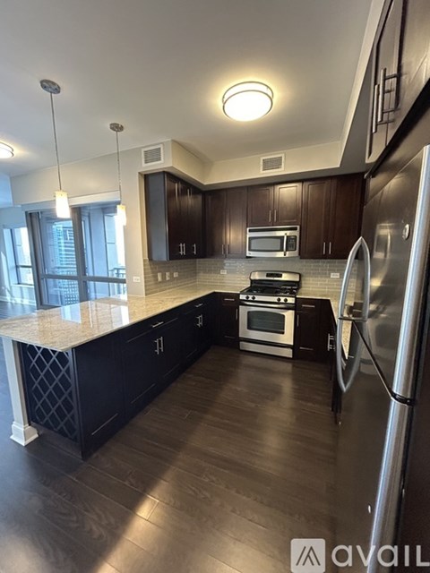 A modern kitchen with dark wood cabinets and stainless steel appliances.