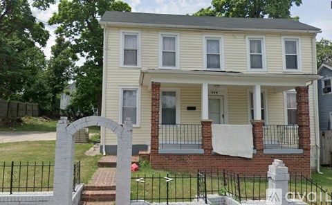 A two-story house with a front porch and a black fence.