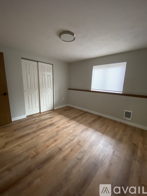 A room with wooden floors and a window with blinds.