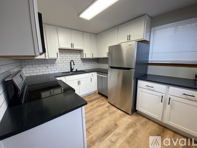 A kitchen with white cabinets and a black countertop.