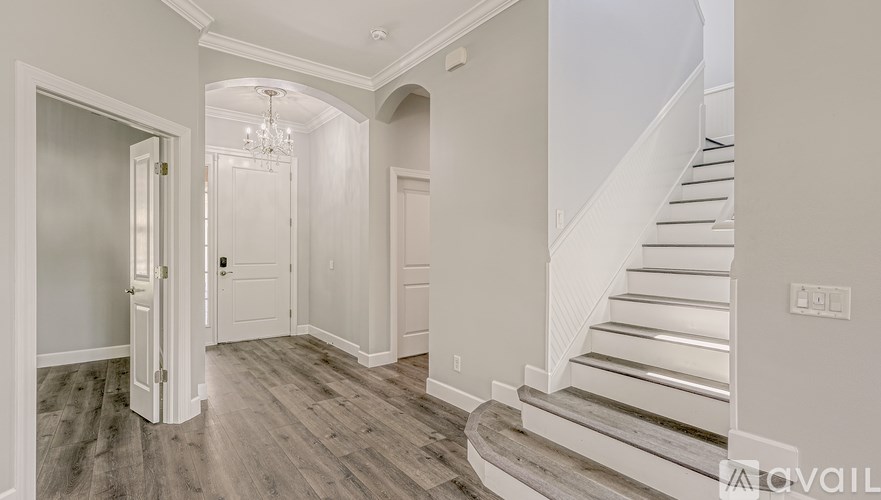 A hallway with a staircase and a chandelier.