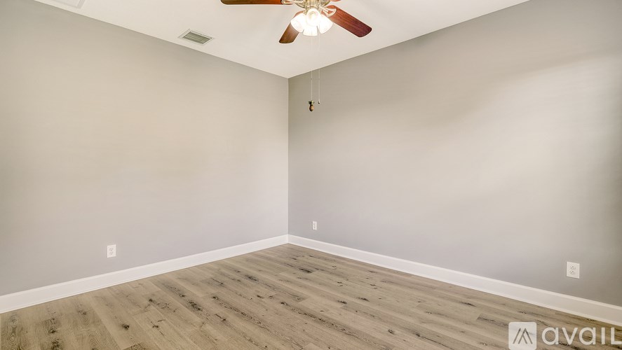 A room with a ceiling fan and wooden flooring.