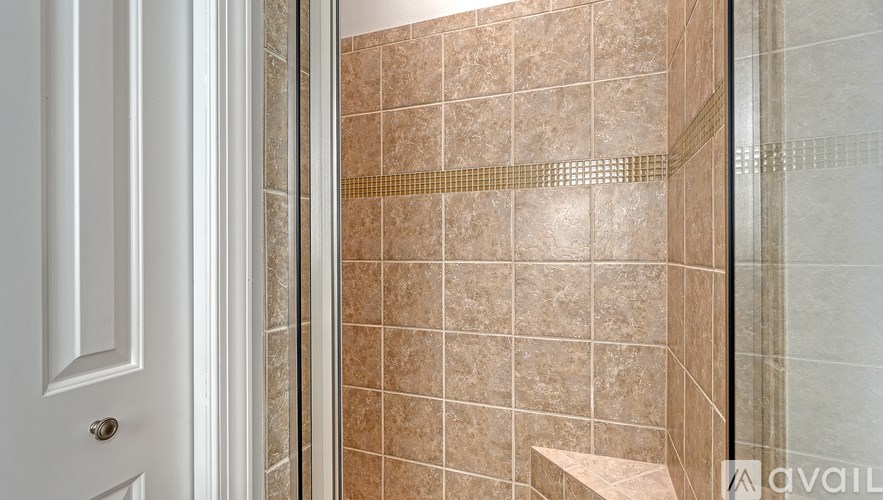 A bathroom with a tiled shower and a white door.
