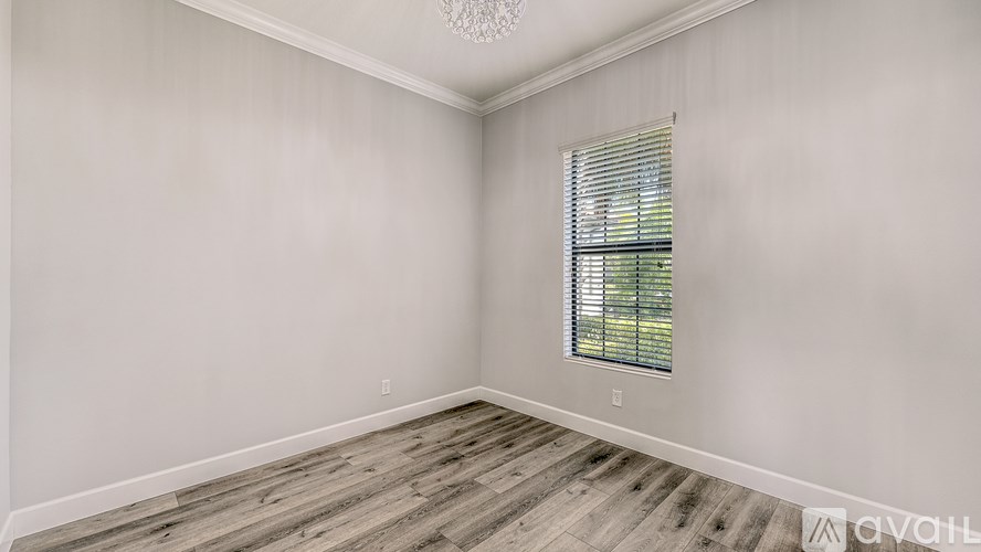 A room with wooden flooring and a window with blinds.