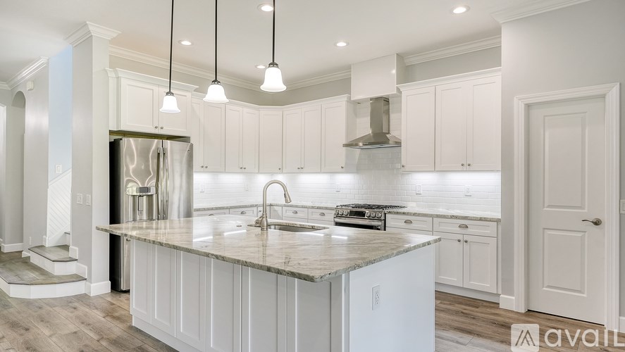 A kitchen with a large island and pendant lights.