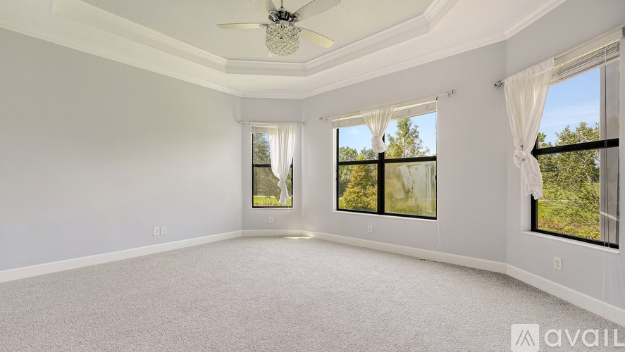 A spacious room with a ceiling fan and large windows.