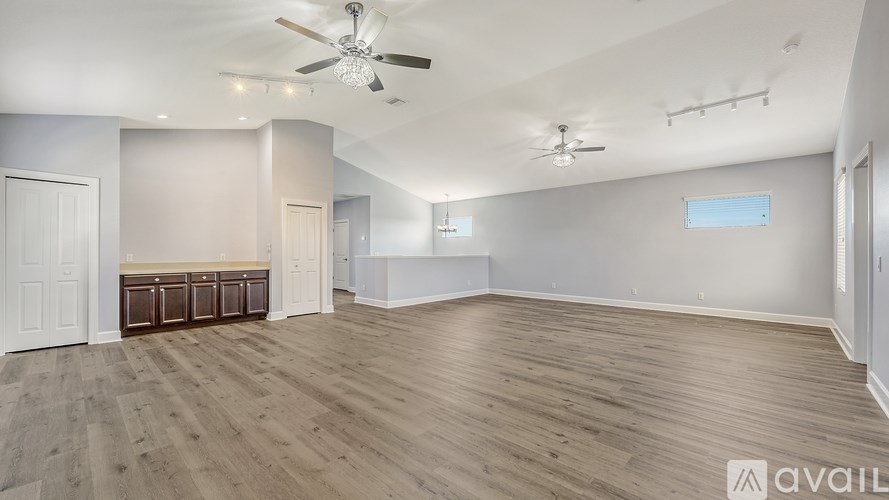 A spacious room with wooden flooring and two ceiling fans.