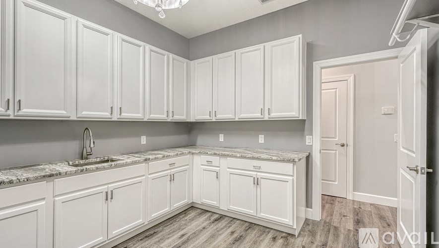 A kitchen with white cabinets and a marble countertop.