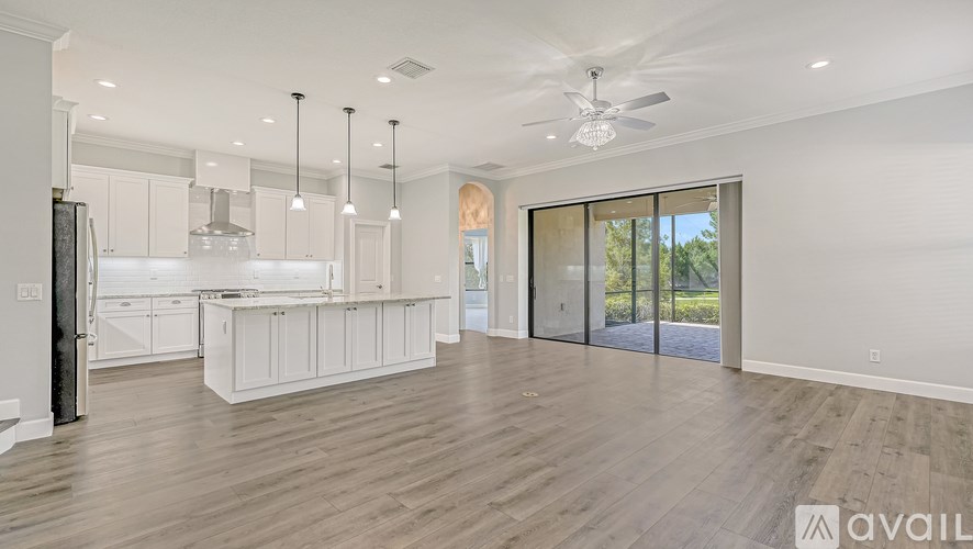 A spacious kitchen with white cabinets and a black refrigerator.