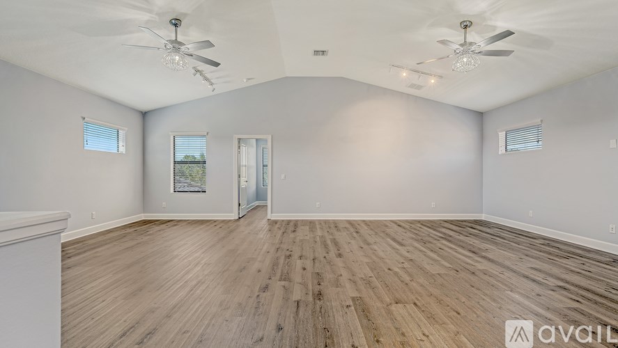 A spacious room with wooden floors and two ceiling fans.