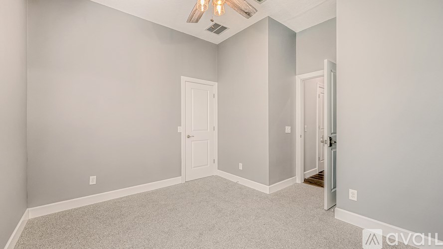 A room with a carpeted floor and a ceiling fan.