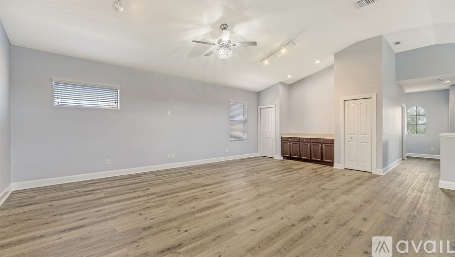 A spacious room with wooden flooring and a ceiling fan.