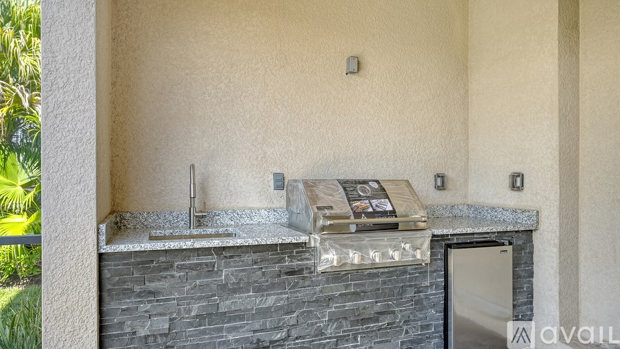 A modern outdoor kitchen with a stone counter and a built-in grill.