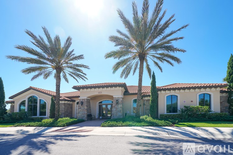 A house with a driveway and two palm trees in front.