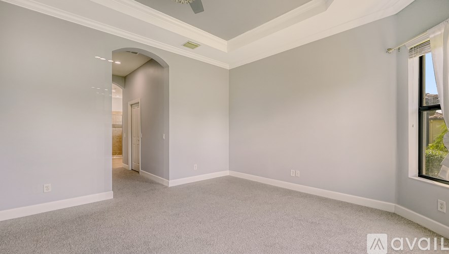 A spacious room with a carpeted floor and a ceiling fan.