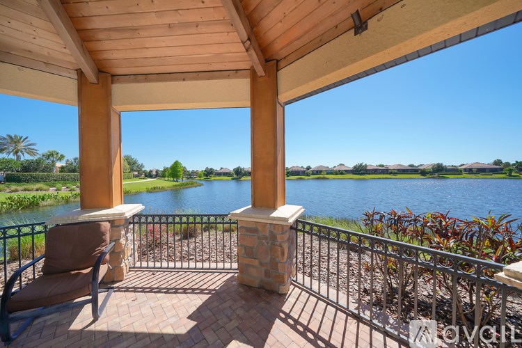 A patio with a chair and a table overlooking a body of water.