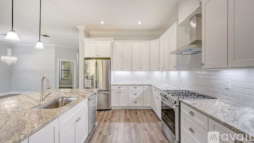 A kitchen with white cabinets and a marble countertop.