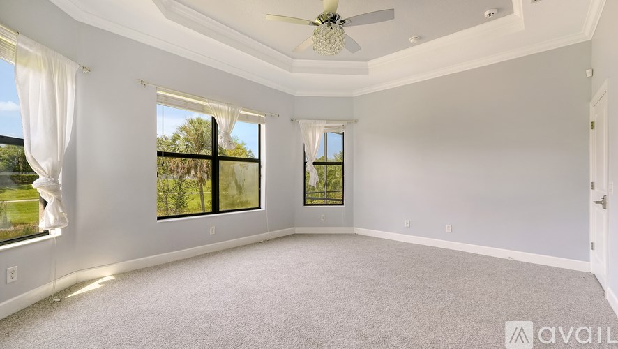 A spacious room with a ceiling fan and large windows overlooking a garden.