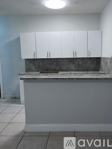 A kitchen with white cabinets and a marble countertop.