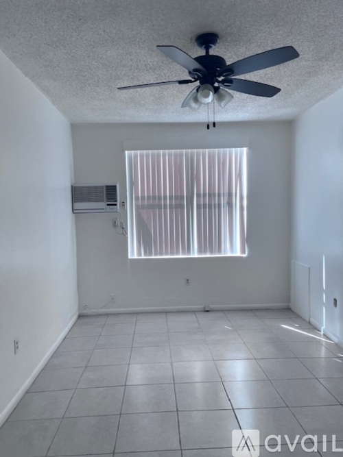 A room with a ceiling fan and a window with blinds.