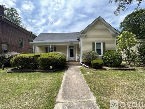 A house with a front yard and a concrete pathway leading to the front door.