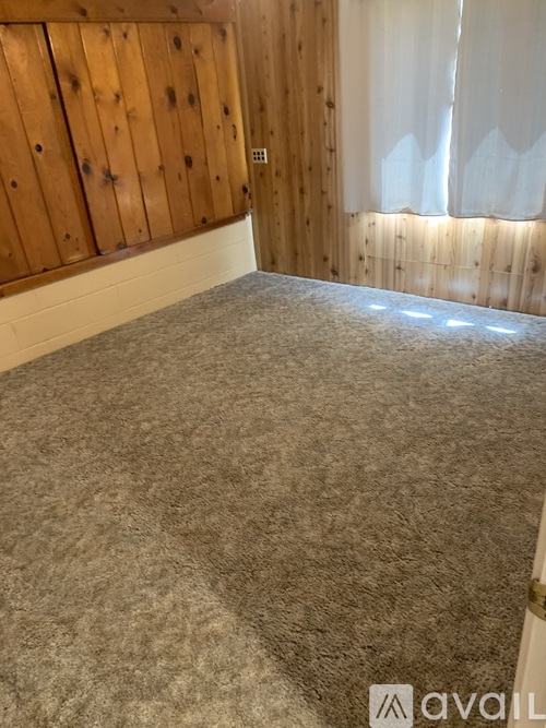 A bedroom with a bed covered in a grey blanket.