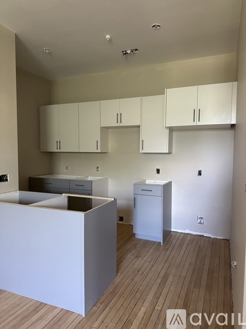 A kitchen with white cabinets and a wooden floor.
