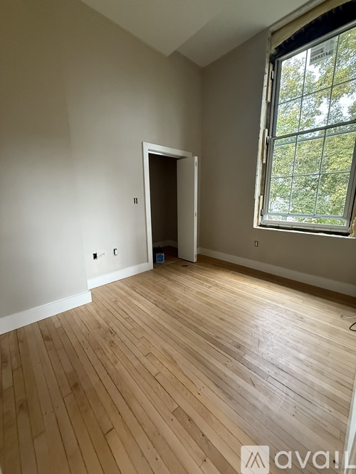 A spacious room with wooden flooring and white walls is available for rent.