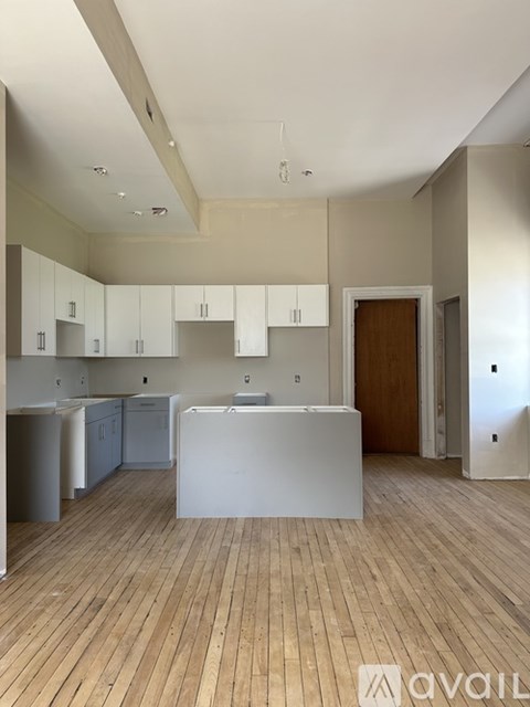 A kitchen with white cabinets and a wooden floor.