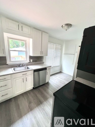 A kitchen with white cabinets and a black counter.