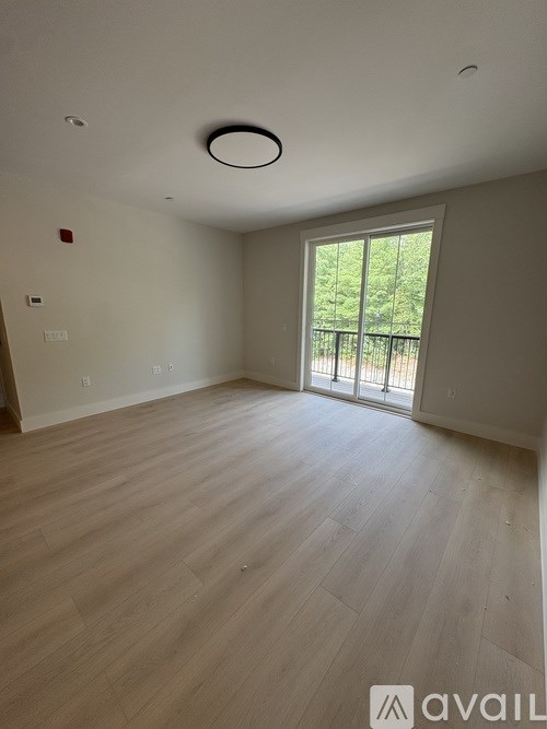 A room with wooden flooring and a sliding glass door leading to a balcony.