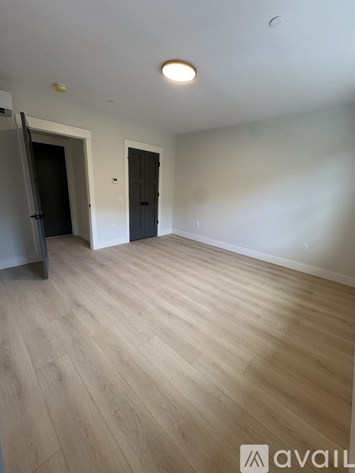 A room with wooden flooring and two doors.